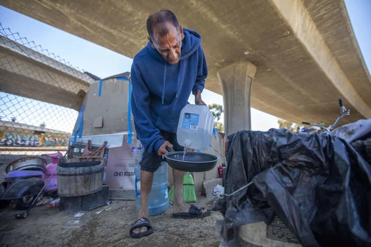 Jose Luis Camargo washes out a skillet outside his makeshift tent in Los Angeles