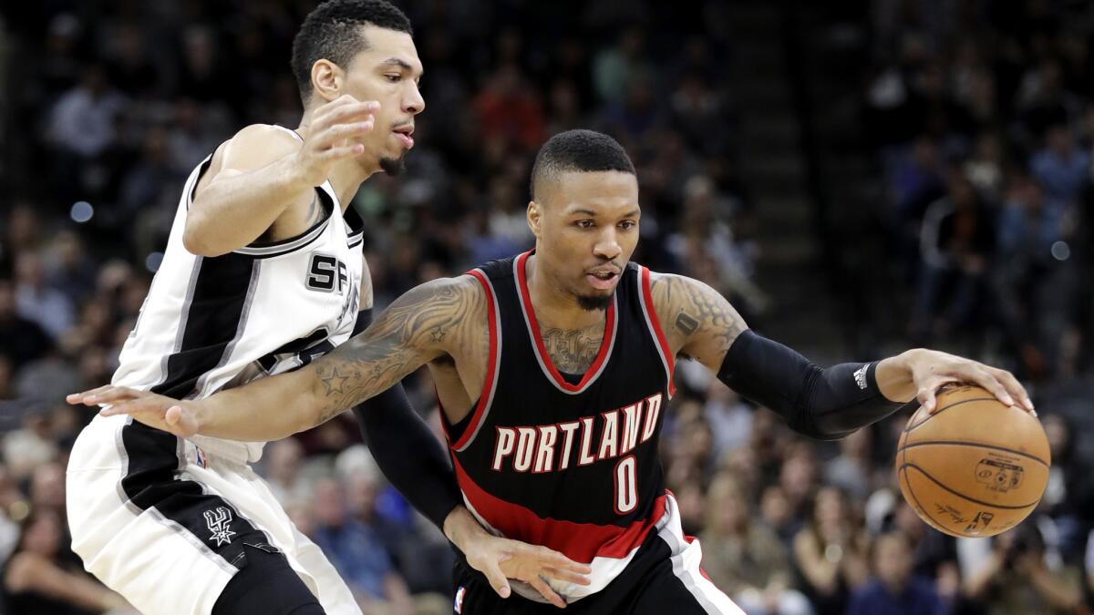 Trail Blazers guard Damian Lillard (0) drives around Spurs guard Danny Green during the second half Wednesday night.