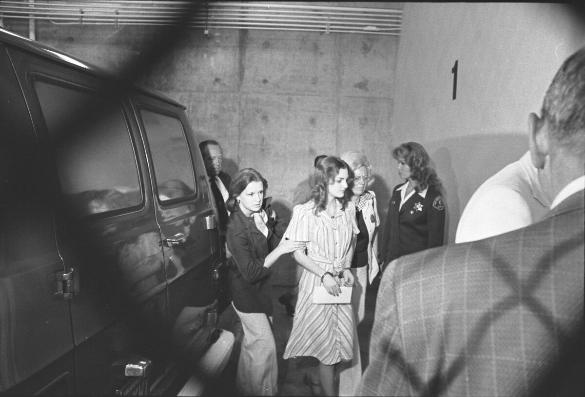 Patty Hearst in handcuffs, escorted by two women