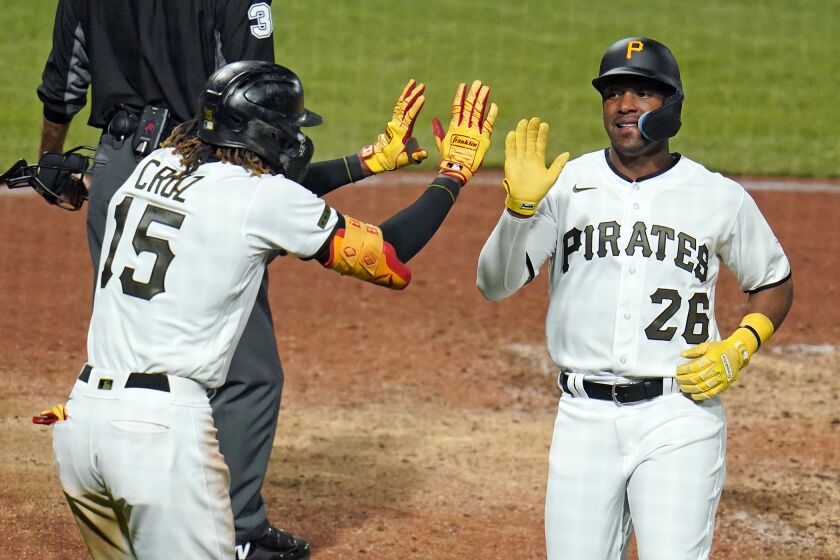 Pittsburgh Pirates' Miguel Andujar (26) and Oneil Cruz (15) celebrate after scoring on a double by Jack Suwinski off Cincinnati Reds relief pitcher Derek Law during the seventh inning of a baseball game in Pittsburgh, Monday, Sept. 26, 2022. (AP Photo/Gene J. Puskar)