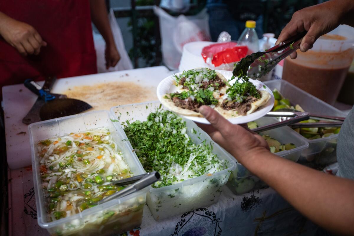 A customer tops off his tacos in South Los Angeles in 2023.