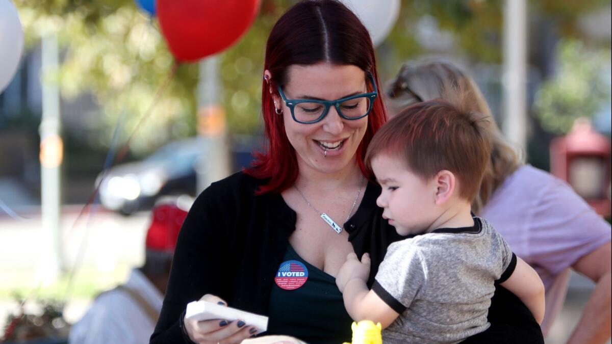 Jessica Collette of Burbank grabbed an ice cream for her 20-month old son Kingston Collette outside the Buena Vista Library polling location in Burbank on Tuesday. A table providing free food and ice cream was provided by Stratiscope for its Party at the Polls event.