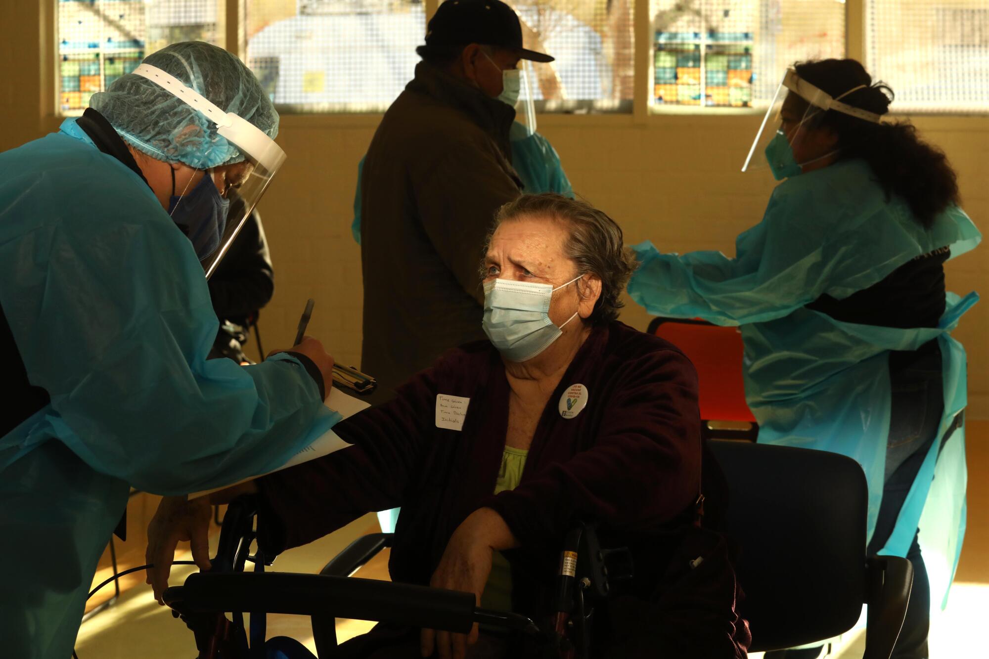 A medical assistant asks Ana Canales, 78, how she is feeling after after receiving the Moderna COVID-19 vaccine.