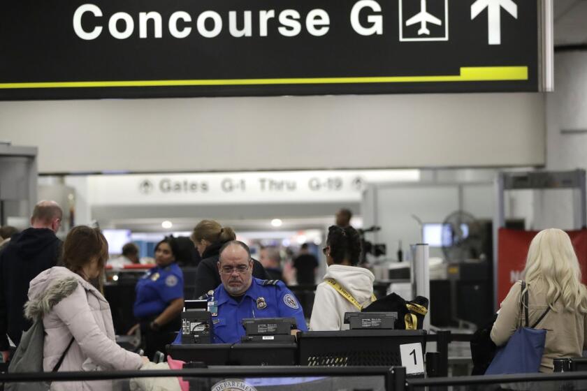 A Transportation Security Administration official works at the entrance to Concourse G at Miami International Airport, Friday, Jan. 11, 2019, in Miami. The airport is closing Terminal G this weekend as the federal government shutdown stretches toward a fourth week because security screeners have been calling in sick at twice the airport's normal rate. (AP Photo/Lynne Sladky)