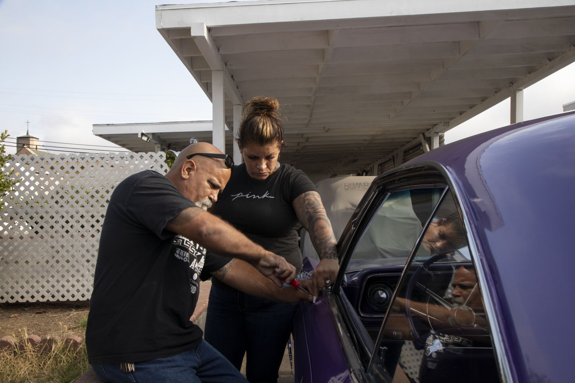 Sofia Toral, 40, helps her father, Robert, install a mirror on her 1965 Impala. 