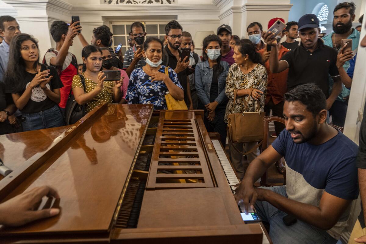 A man plays piano at the prime minister's official residence on the second day after it was it was stormed in Colombo, Sri Lanka, Monday, July 11, 2022. Sri Lanka is in a political vacuum for a second day Monday with opposition leaders yet to agree on who should replace its roundly rejected leaders, whose residences are occupied by protesters, angry over the country's economic woes. (AP Photo/Rafiq Maqbool)