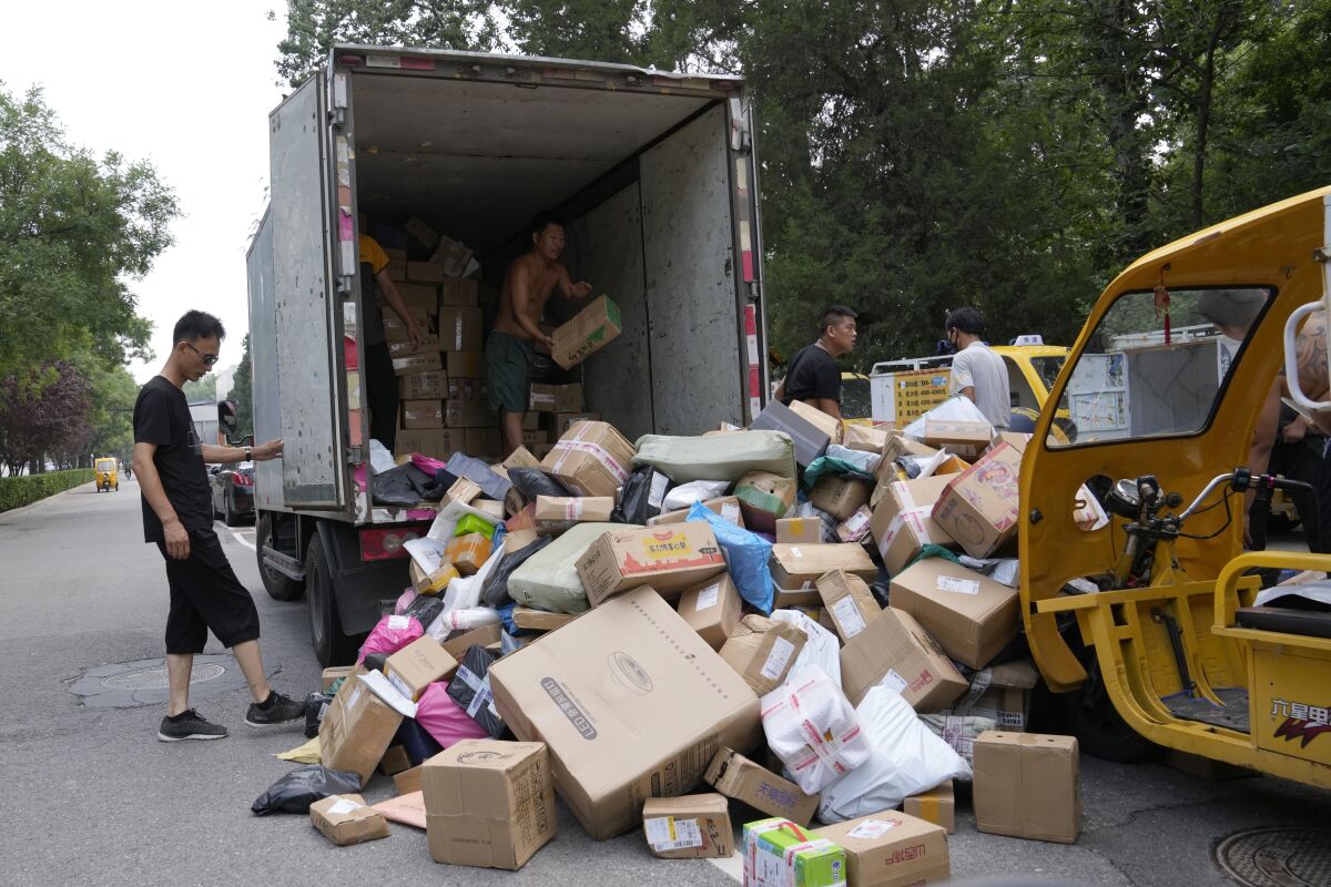 Workers sort out parcels for delivery in Beijing Wednesday, July 14, 2021. China's economic growth slowed to a still-strong 7.9% over a year ago in the three months ending in June as a rebound from the coronavirus leveled off. (AP Photo/Ng Han Guan)