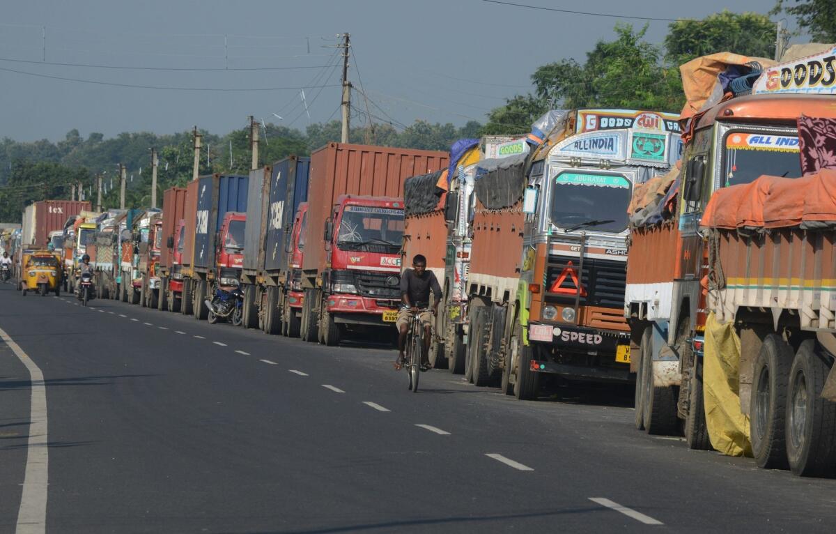 An Indian man cycles past parked Indian trucks carrying goods to Nepal near the India-Nepal border at Panitanki on Tuesday.