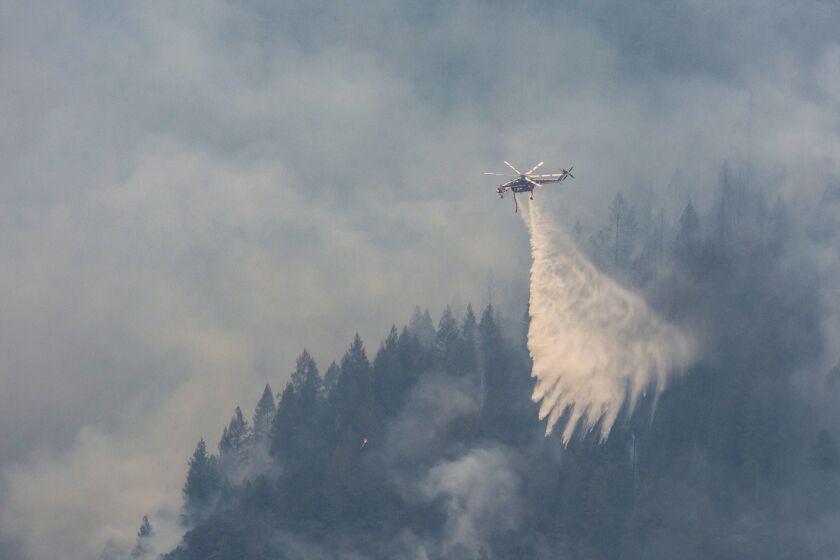 A Sikorsky S-64 "Skycrane" drops water on a ridge near Baltimore Mine Road during the Mosquito Fire on Sunday, Sept. 11, 2022. The Mosquito Fire has grown to 78 square miles (200 square kilometers), with 18% containment, according to the California Department of Forestry and Fire Protection. (Sara Nevis/The Sacramento Bee via AP)