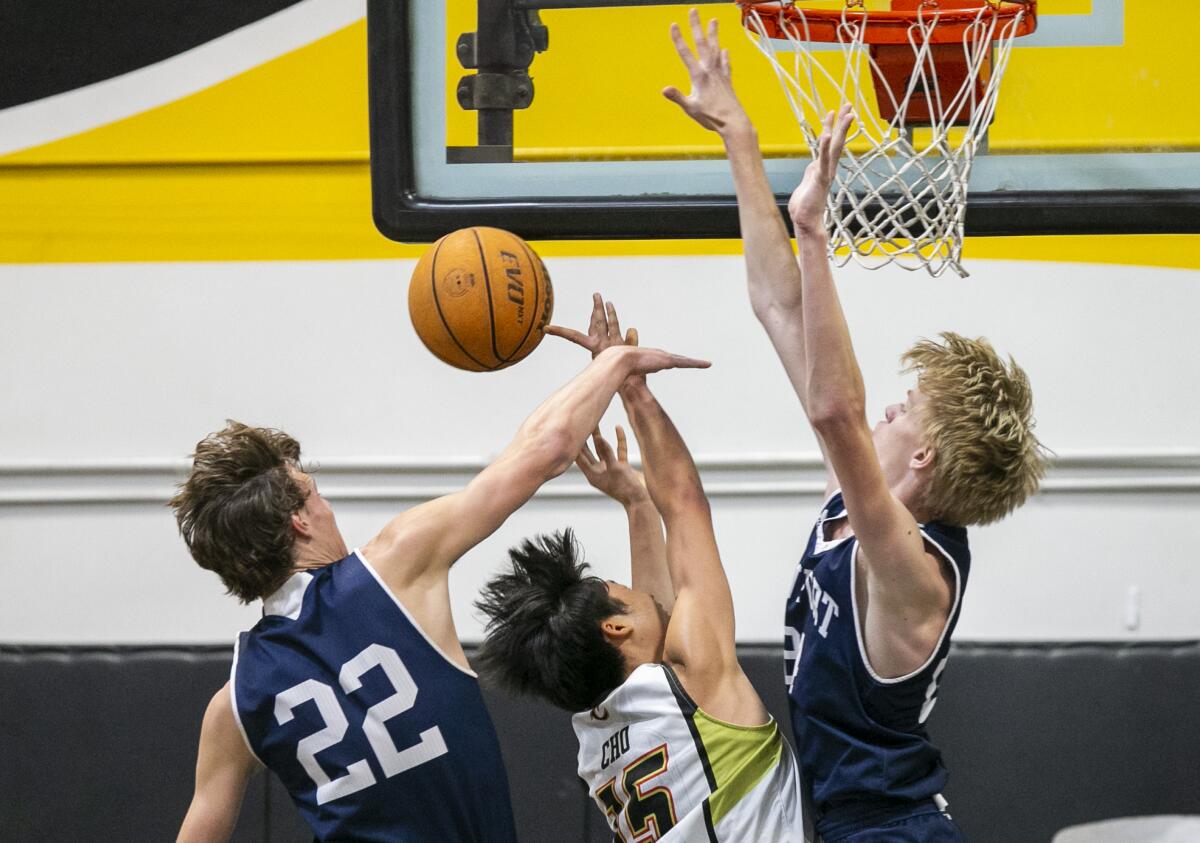 Newport Harbor's Guy Riggs, left, and Adam Gaa block a shot by Cerritos' Benson Cho during a playoff game on Friday.