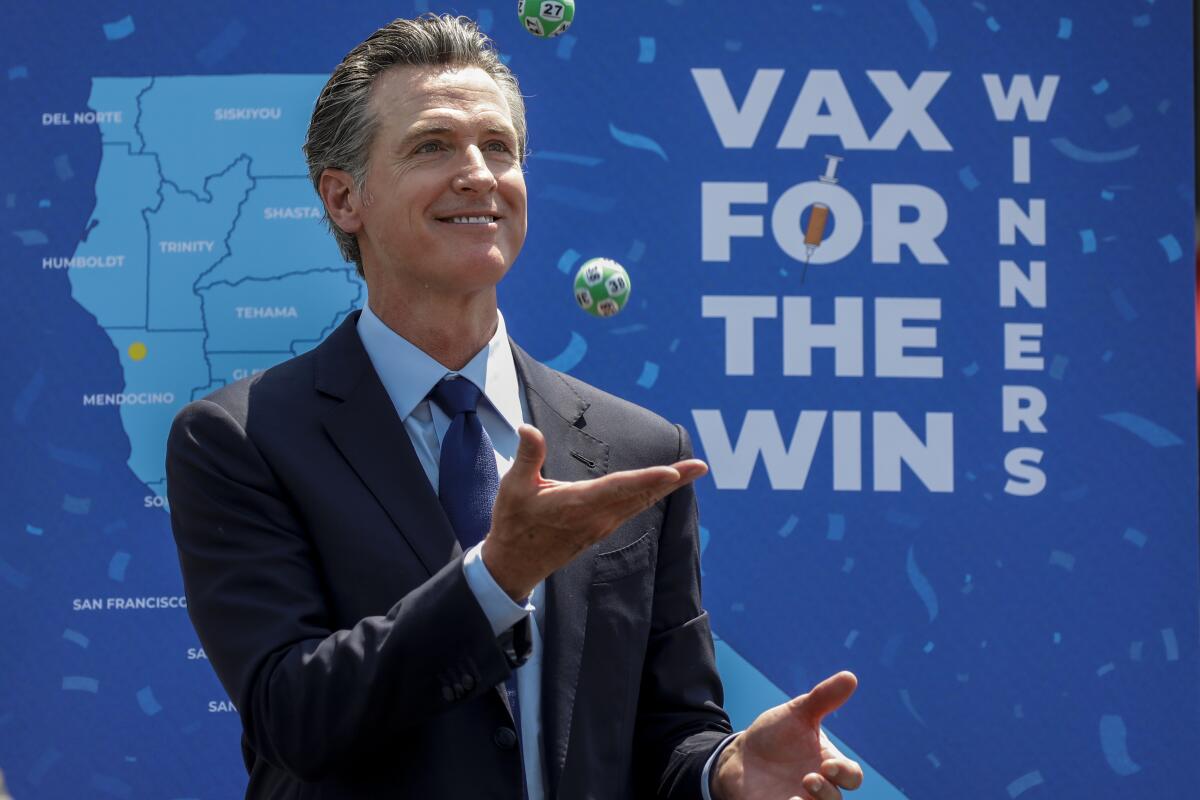 Newsom juggles numbered balls in front of a sign that says "Vax for the Win"