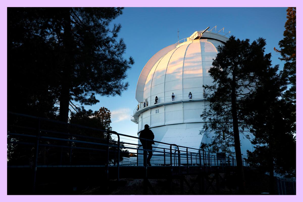 A person in silhouette in front of the dome of an observatory with several people standing around the dome