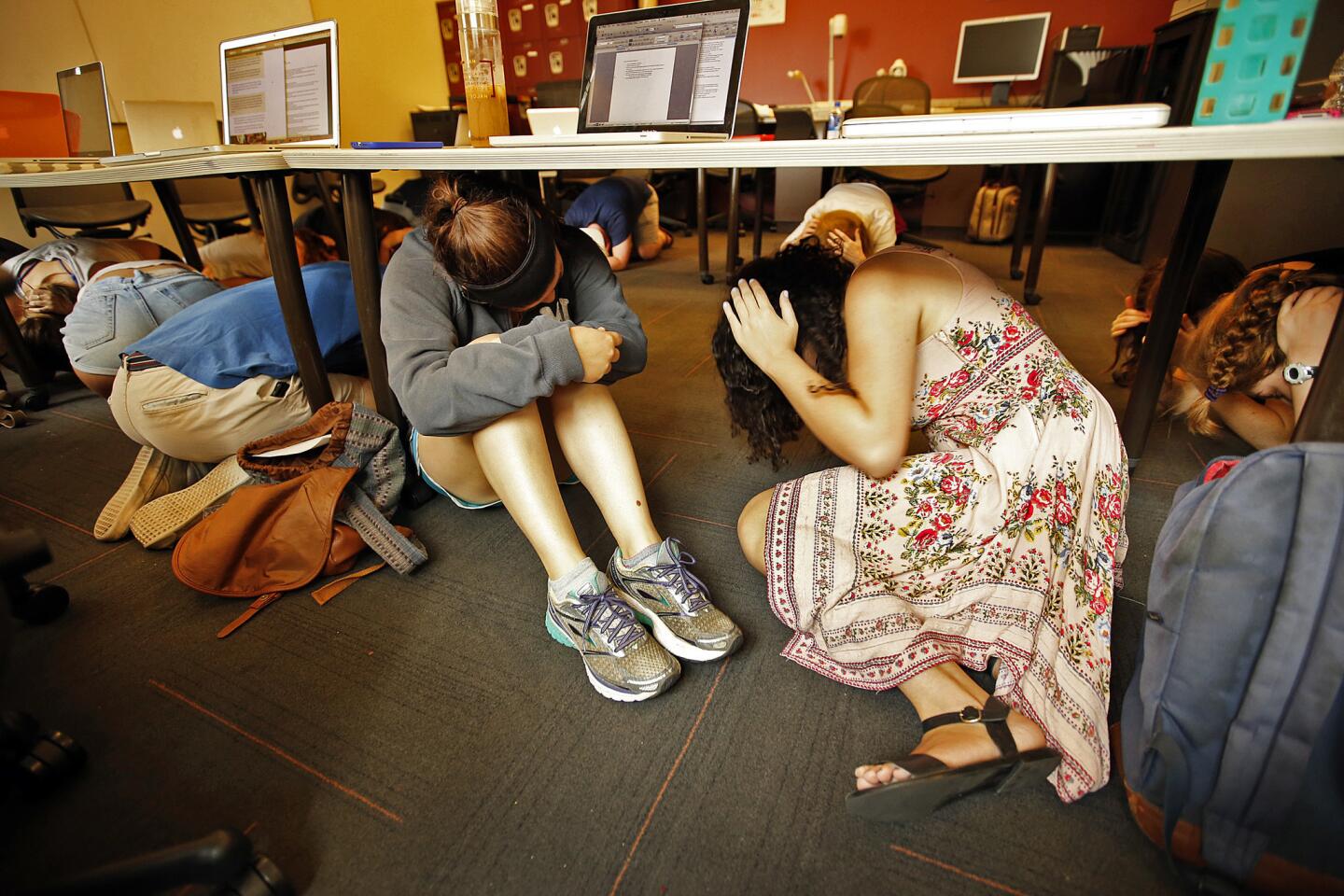 USC cinema students Julia Epstein-Norris, left, Esme Douglas and their classmates drop and cover under desks during their TV spec writing class as the university participates in the eighth-annual Great Shakeout.