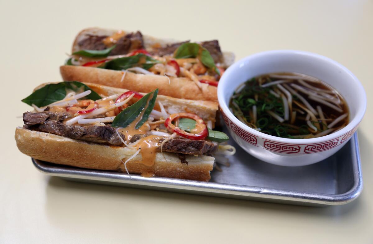 A pho baguette with beef brisket, basil, onions, and hoisin sriracha sauce is served with a side car of pho for dipping at East Borough in Culver City.