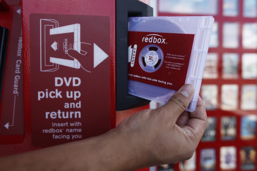 A rental DVD is dispensed from a Redbox, a $1-per-night DVD movie rental kiosk, at a 7-Eleven in Silver Lake area of Los Angeles on Friday, August 7, 2009. Redbox, has 17,900 kiosks in the U.S. and expects to add up to 8,500 more this year, nearly one every hour. (AP Photo/Damian Dovarganes)