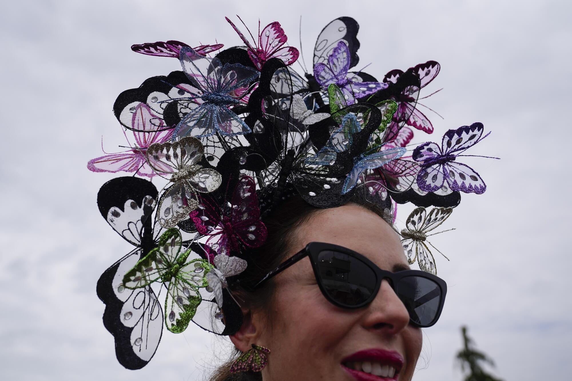 A woman with a hat featuring butterflies walks on the grounds of Churchill Downs on Saturday.