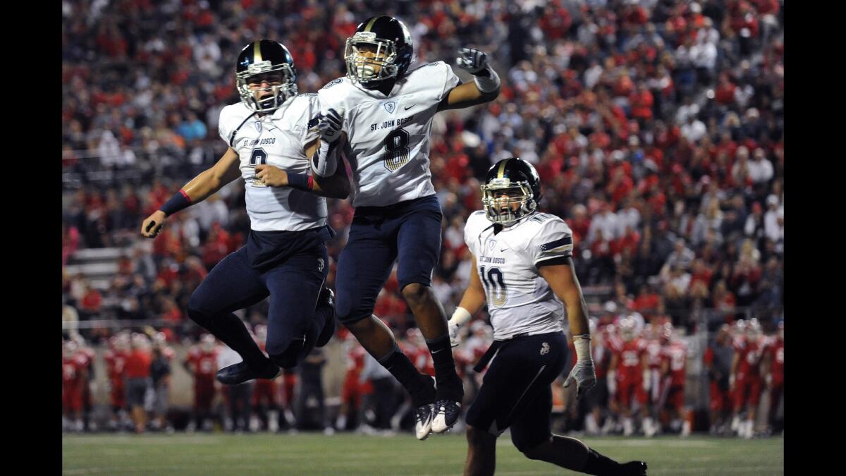 St. John Bosco's Cross Poyer, center, celebrtes his touchdown with quarterback Quentin Davis, left, after scoring against Mater Dei in a Trinity League game Oct. 16.