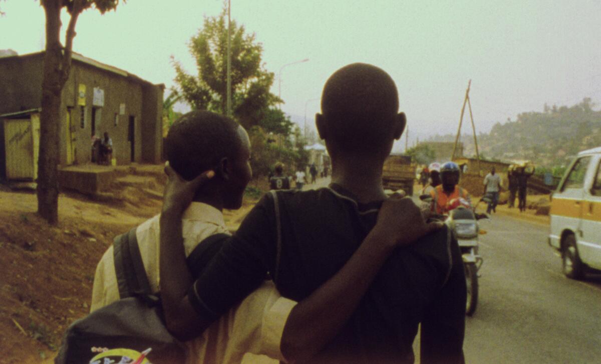 Two young men with their arms around each other walk down a street