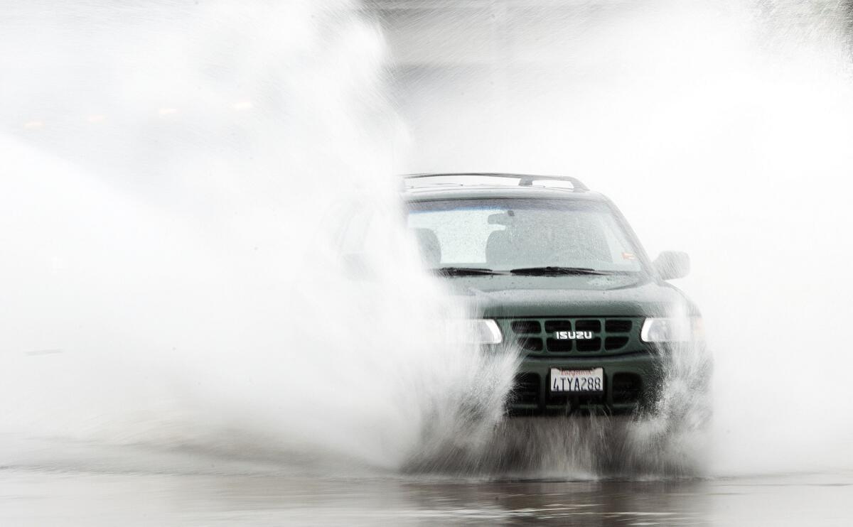 A motorist hits a large puddle on West Garden Grove Boulevard in Garden Grove. National Weather Service meteorologists say the rain and snow California is seeing may help the state's drought picture.