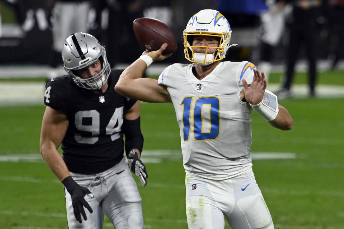 Chargers quarterback Justin Herbert looks to pass under pressure from Raiders defensive end Carl Nassib.