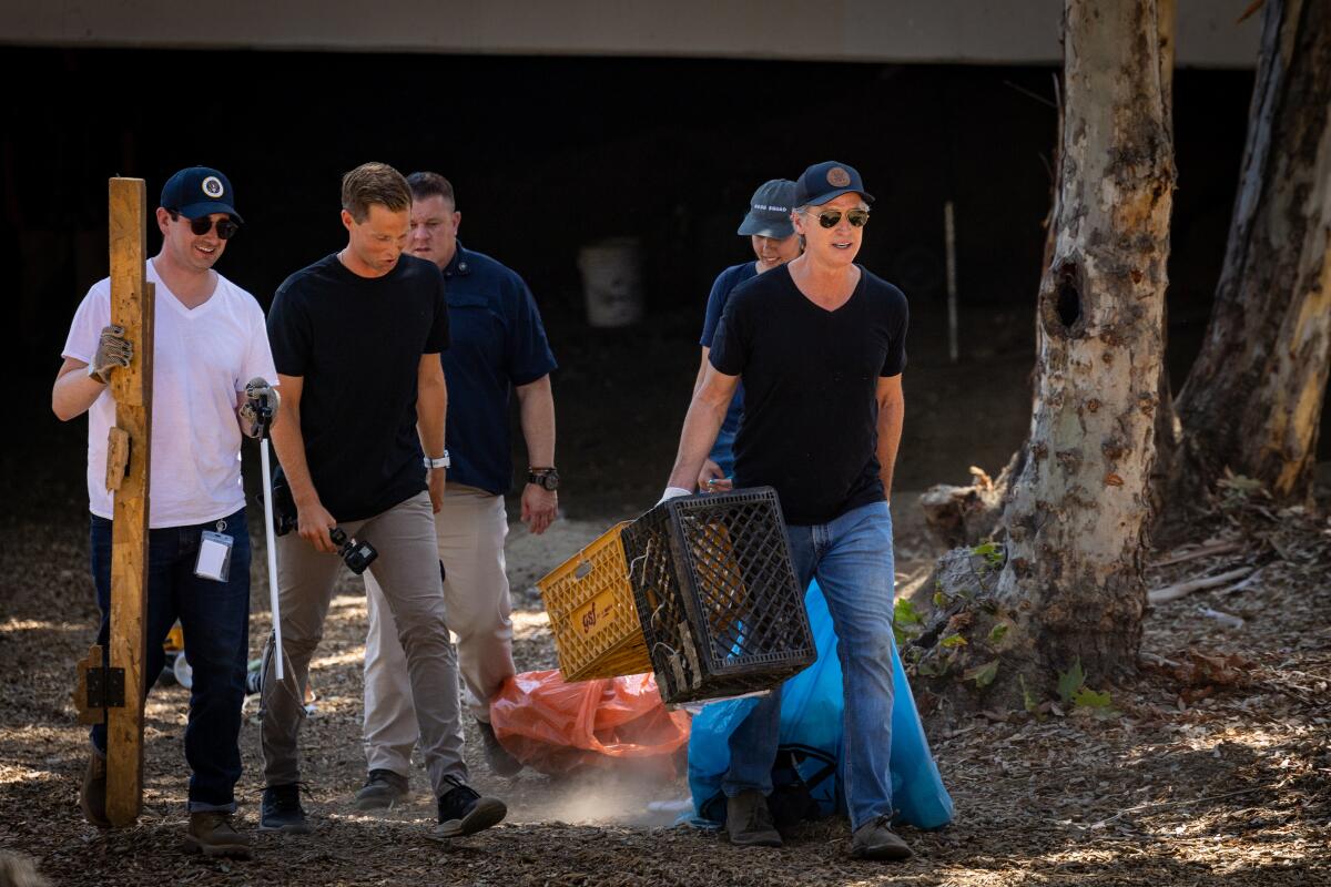 Gov. Newsom, right, participated in a clean up of an encampment site near Paxton Street and Remick Avenue in Los Angeles.