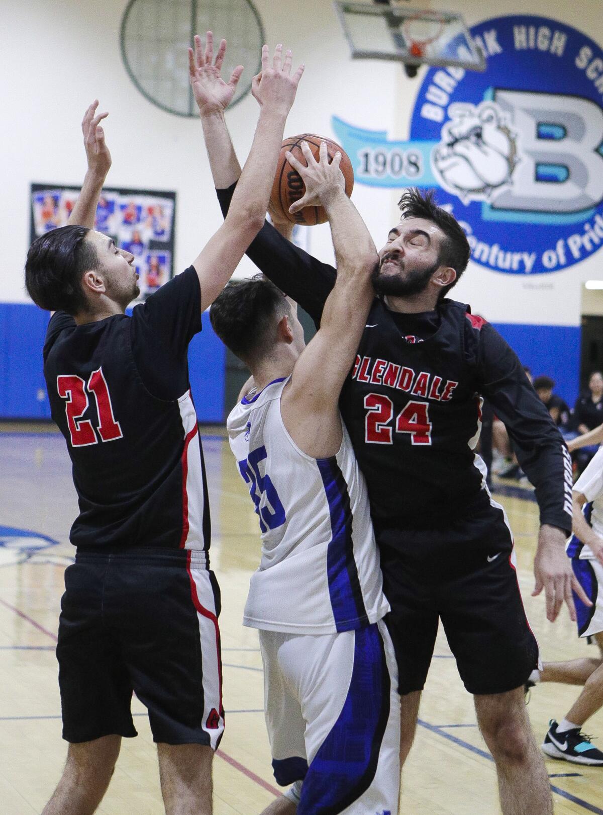 Burbank's Abiel Pearl comes down with a rebound between Glendale's Manouk Manoukian and David Shamiryan in a Pacific League boys' basketball game at Burbank High School on Friday, January 17, 2020.
