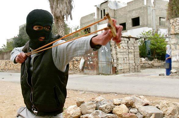 A Palestinian demonstrator uses a slingshot to hurl a stone during a protest against the construction of Israel's separation barrier in Qalqilya, West Bank.