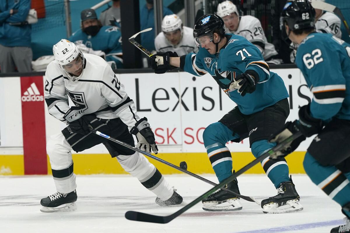 Kings left wing Andreas Athanasiou reaches for the puck next to San Jose Sharks defenseman Nikolai Knyzhov.