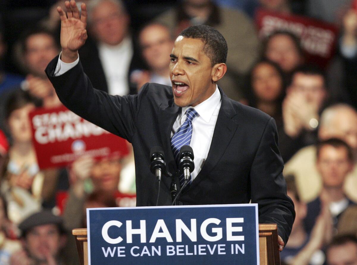 Barack Obama addresses a crowd at a lectern with a sign that says, "Change we can believe in"