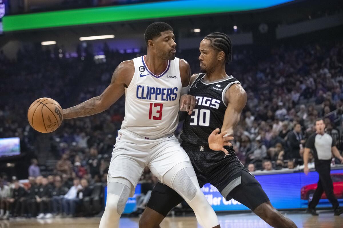 Clippers guard Paul George, left, controls the ball in front of Sacramento Kings forward KZ Okpala.