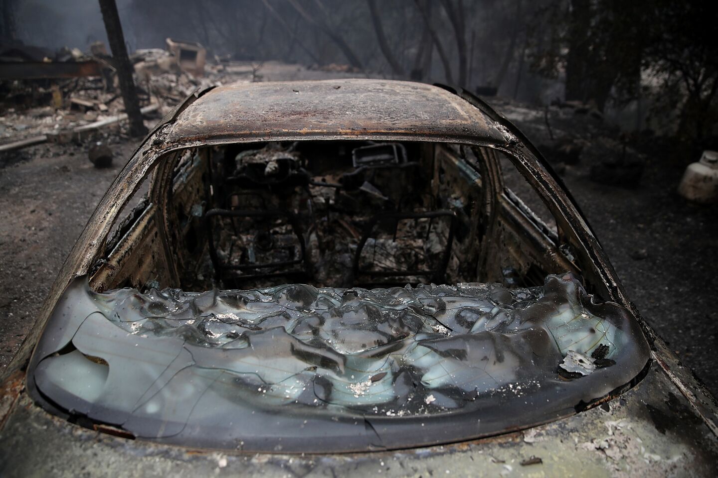 A burned-out car sits next to a home that was destroyed by the Detwiler Fire in Mariposa, Calif.
