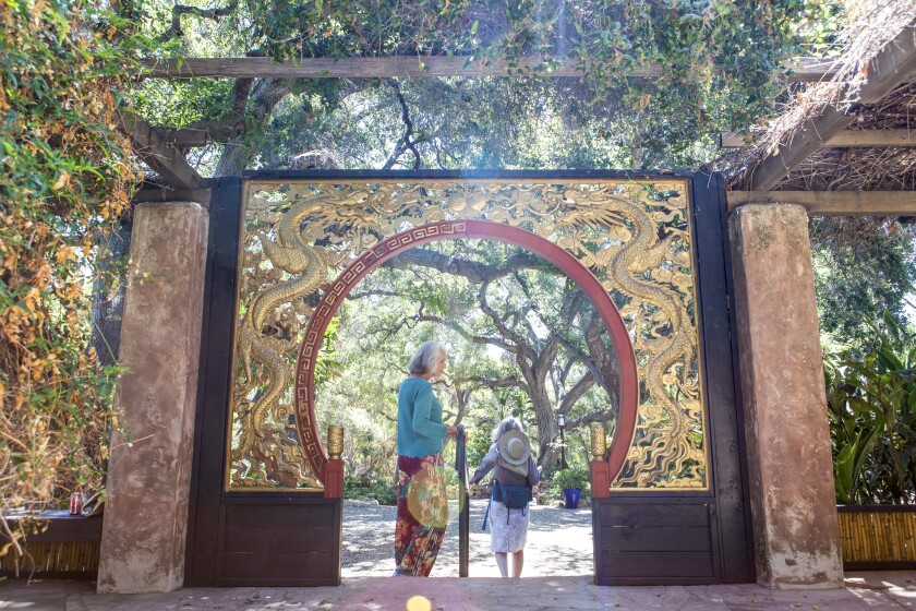 Two people stand under an arch carved with dragons
