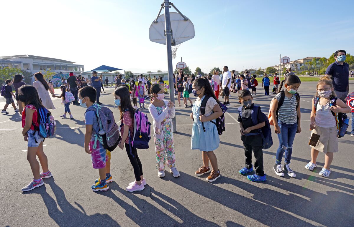 Masked students line up for their first day of school last July at Enrique S. Camarena Elementary School in Chula Vista.