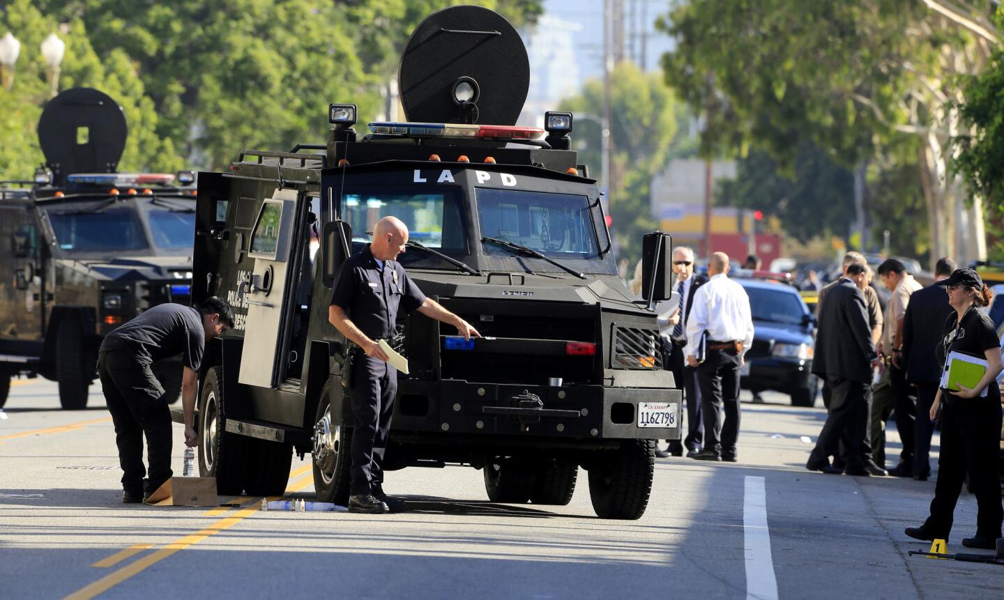 Los Angeles Police Cmdr. Andrew Smith looks at the damage to an LAPD BearCat, a wheeled armored personnel carrier, after an officer involved shooting that killed a man early Monday morning.