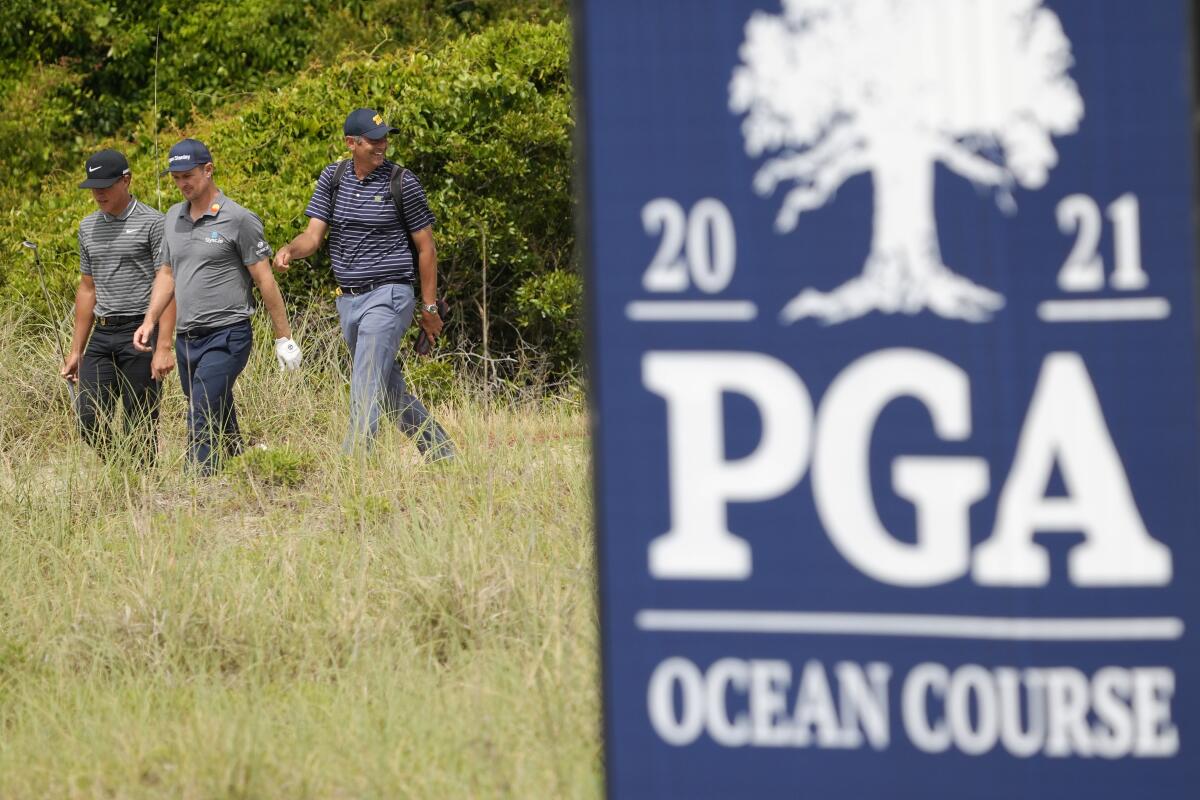 Justin Rose, left, of England, and Cameron Champ, middle, walk to the 14th green during a practice round at the PGA Championship golf tournament on the Ocean Course Wednesday, May 19, 2021, in Kiawah Island, S.C. (AP Photo/David J. Phillip)