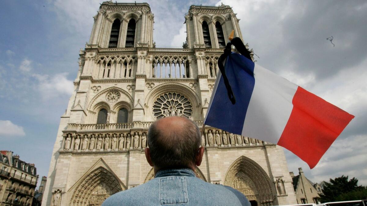A man stands with the French flag in front of Notre Dame Cathedral in Paris on June 3, 2009.