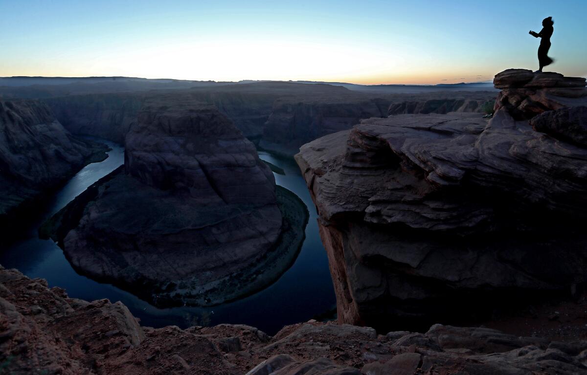 A visitor takes pictures at dusk from an overlook above Horseshoe Bend on the Colorado River near Page.
