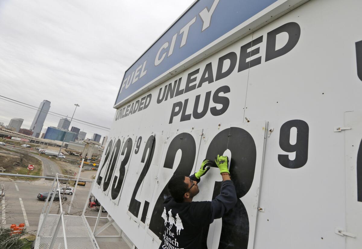 Luis Vargas changes the gas price sign at the Fuel City gas station in Dallas on Dec. 17. Falling gas prices have helped give consumers more spending money.