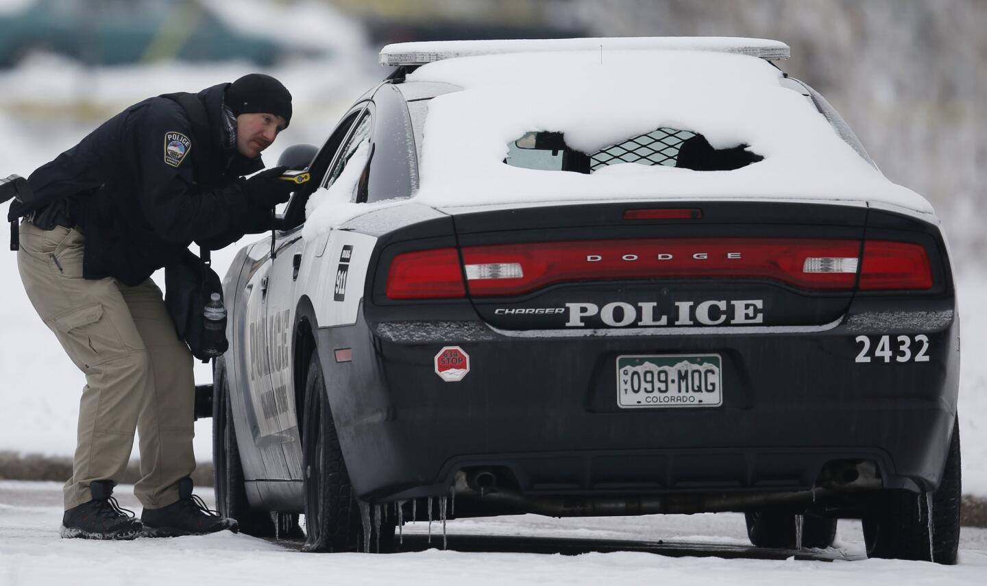 A crime scene investigator looks over a police vehicle damaged during Friday's shooting spree near a Planned Parenthood clinic on Nov. 29, 2015, in northwest Colorado Springs, Colo.