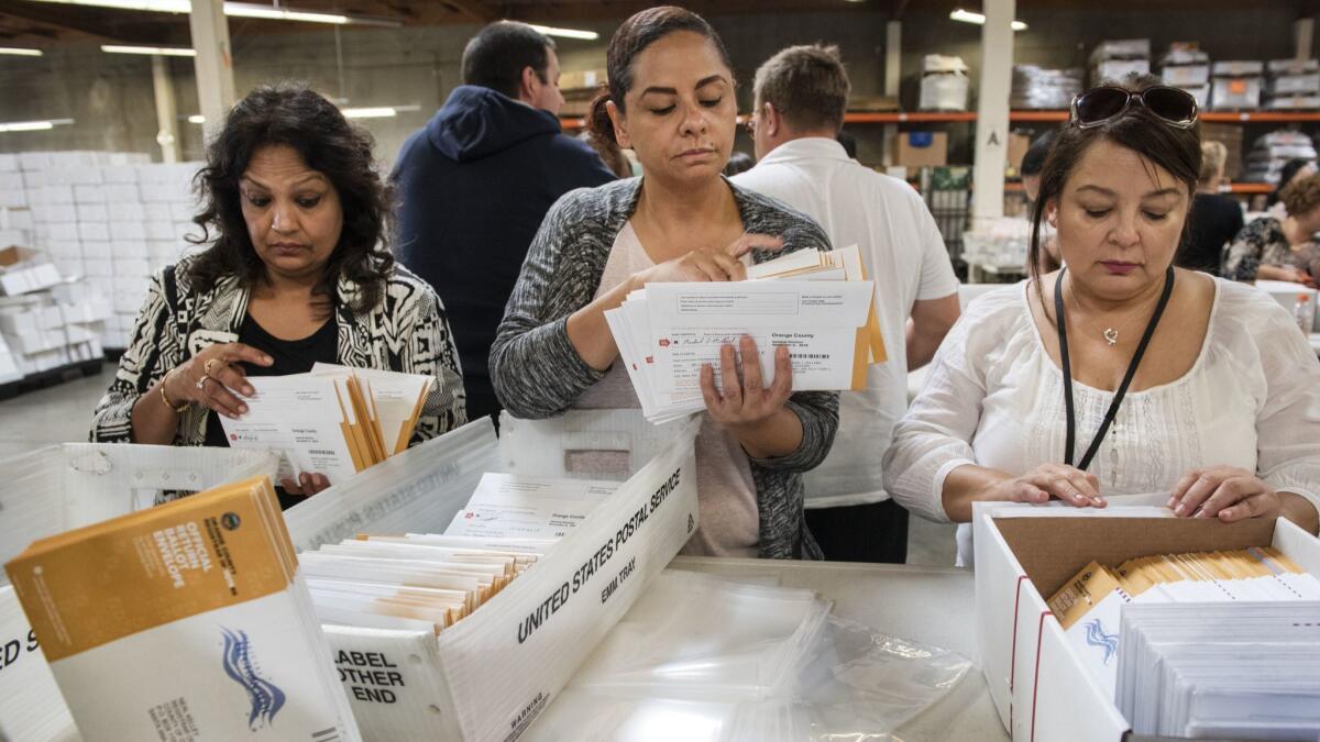 Employees of the Orange County Registrar of Voters sort through mail-in ballots in Santa Ana.
