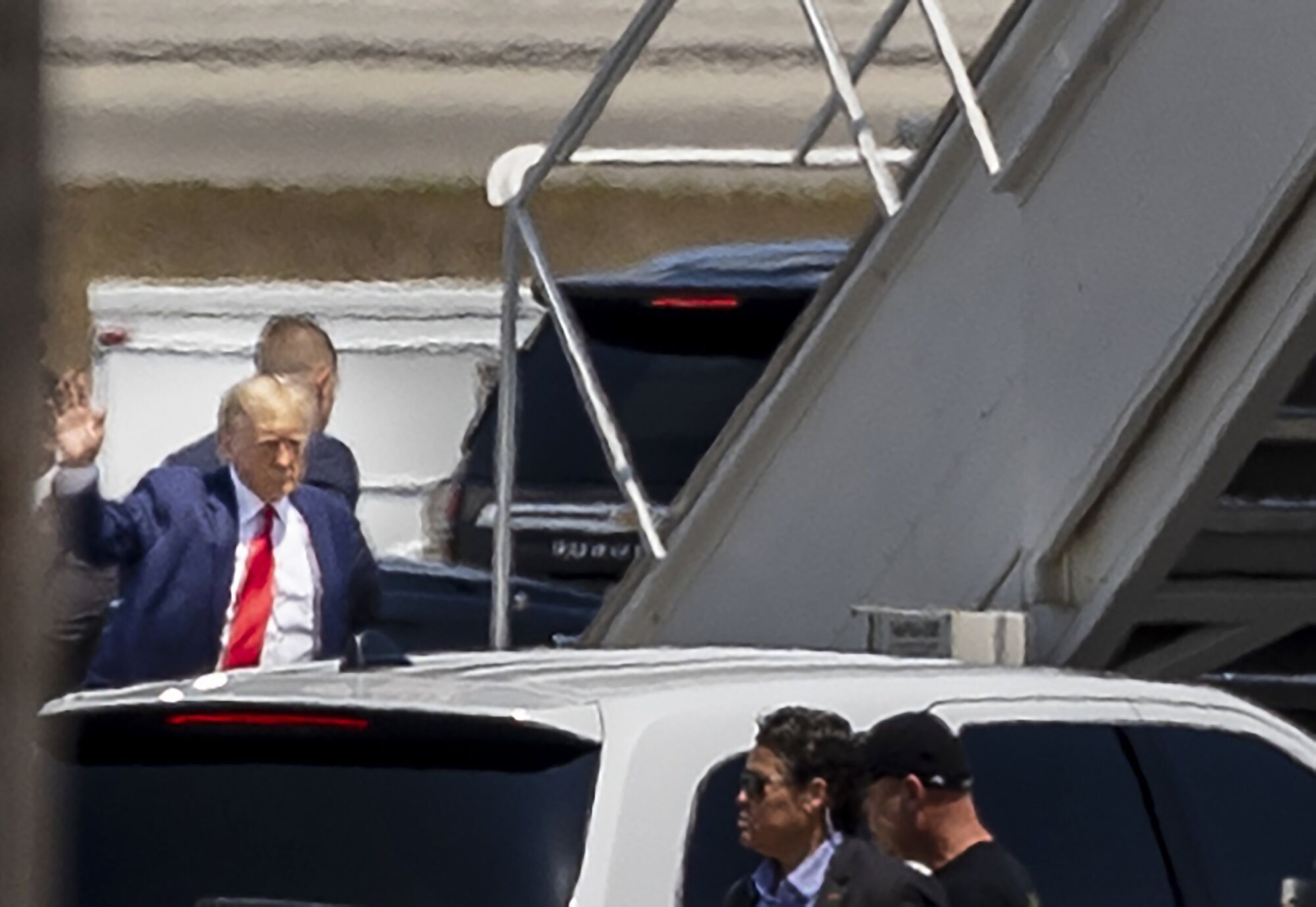 Donald Trump, özel uçağına binmek için merdivenlere yönelirken el sallıyor 