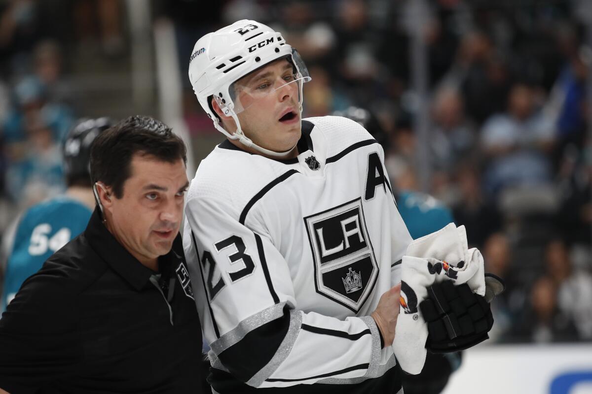 Kings trainer Chris Kingsley, left, escorts right wing Dustin Brown (23) during the second period.