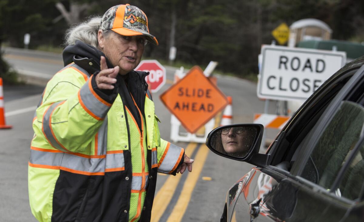 Caltrans contractor Arleen Guzzie directs a motorist to a detour around the road closure on Highway 1 in Big Sur.