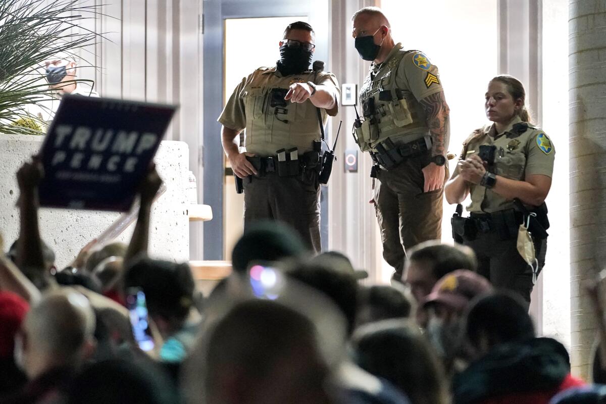 Maricopa County Sheriff's deputies stand outside the County Recorder's Office as Trump supporters rally outside.