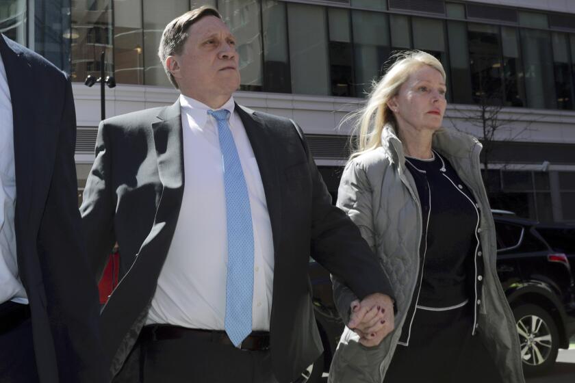 FILE - John Wilson arrives at federal court, with his wife Leslie, on April 3, 2019 to face charges in a nationwide college admissions bribery scandal in Boston. Wilson, a former Staples Inc. executive who was convicted of trying to bribe his children's way into USC, Harvard and Stanford, is scheduled to be sentenced on federal charges Wednesday Feb. 16, 2022. (AP Photo/Charles Krupa, File)