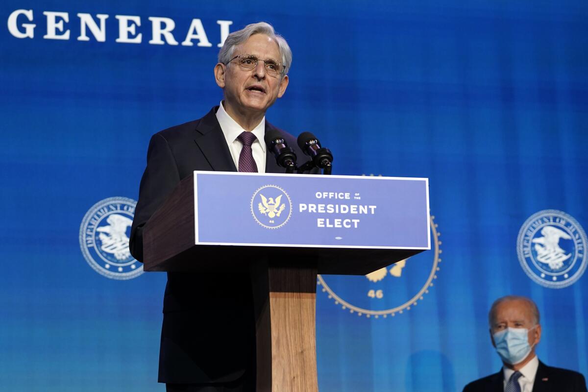 Merrick Garland at a lectern, with Joe Biden at right