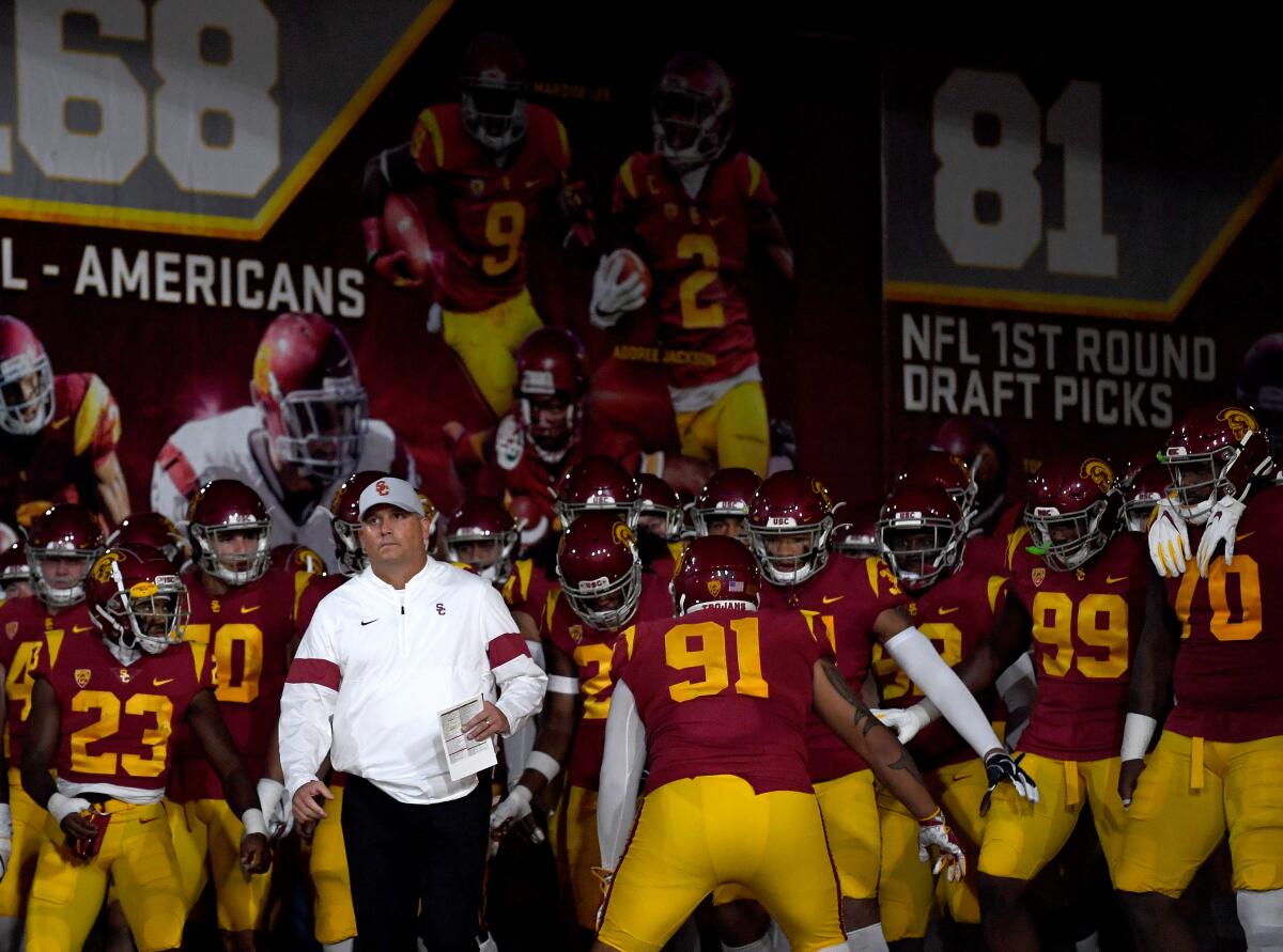 USC coach Clay Helton leads the Trojans onto the field.