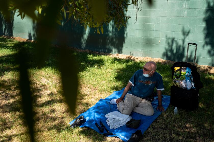 LOS ANGELES, CA - MAY 01: Terrance Whitten, 67, rests in the shade of a tree at Pan Pacific Park on Friday, May 1, 2020 in Los Angeles, CA. Whitten, 67, and is homeless, has been spending his days in the Pan Pacific Park as he has been waiting in the queue for nine days to get into a Project Roomkey hotel room. (Kent Nishimura / Los Angeles Times)