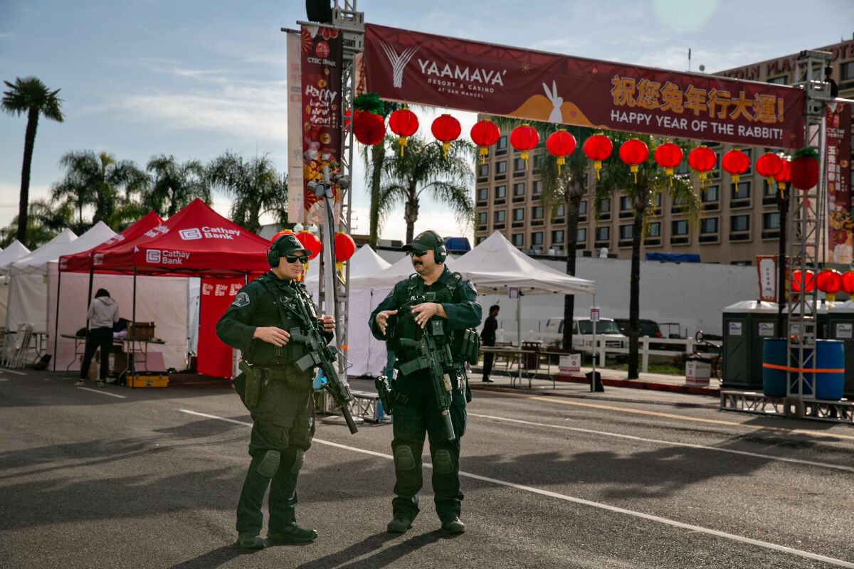 Two armed officers stand in Monterey Park in front of banners celebrating Lunar New Year. 