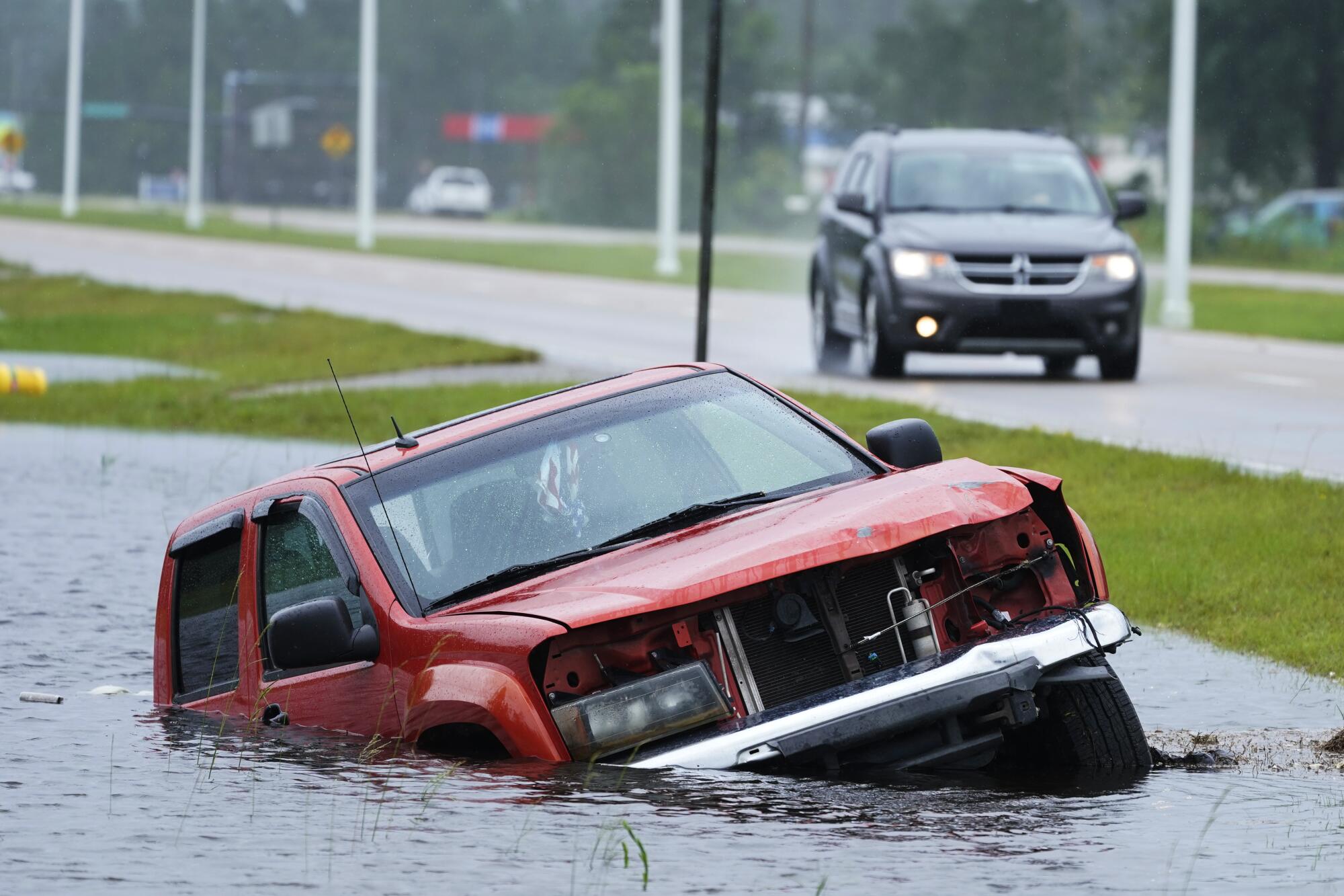 An abandoned vehicle is half-submerged in a ditch.